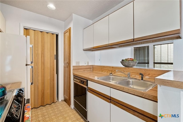 kitchen featuring a sink, white cabinetry, black dishwasher, light countertops, and stainless steel range