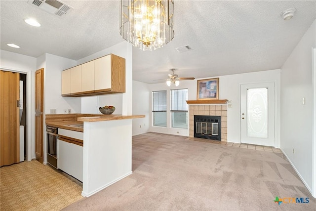 kitchen featuring light carpet, visible vents, open floor plan, and a tiled fireplace