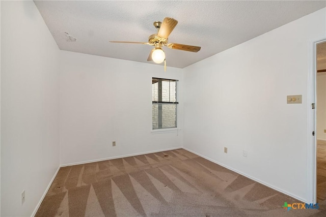 carpeted spare room featuring ceiling fan, a textured ceiling, and baseboards