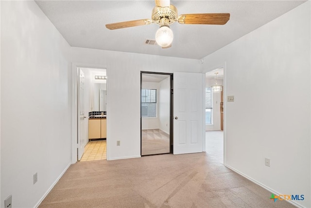 unfurnished room with a ceiling fan, light colored carpet, visible vents, and baseboards