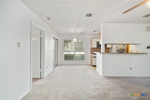 unfurnished living room with visible vents, ceiling fan, light carpet, and a textured ceiling