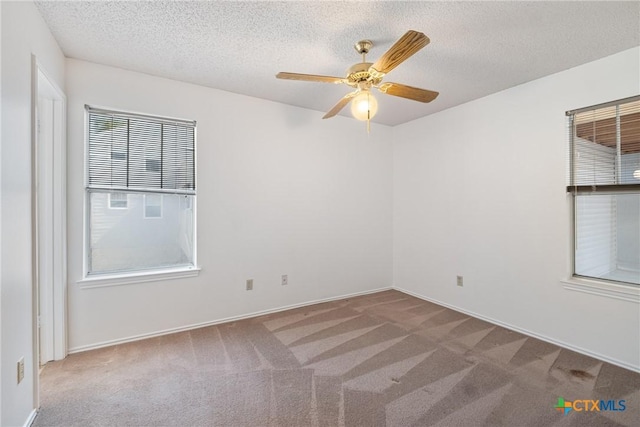 carpeted empty room featuring a textured ceiling, a ceiling fan, and baseboards