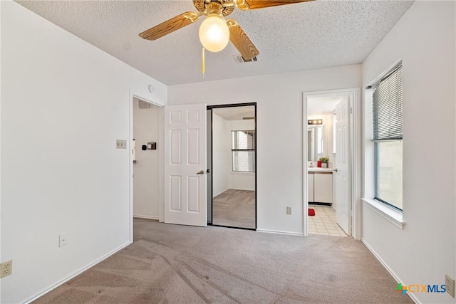 unfurnished bedroom with visible vents, light colored carpet, a textured ceiling, and baseboards