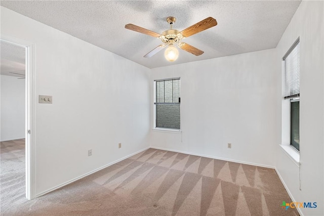 empty room with a textured ceiling, a ceiling fan, and light colored carpet