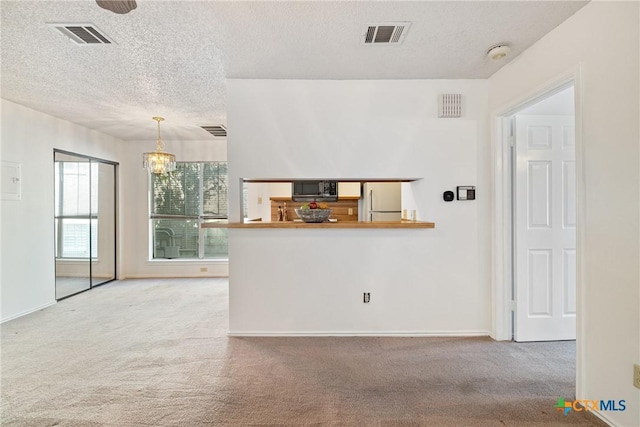 interior space featuring a textured ceiling, visible vents, and carpet flooring