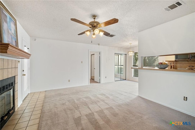 unfurnished living room featuring visible vents, a fireplace, a textured ceiling, and ceiling fan with notable chandelier