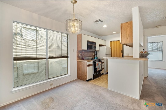 kitchen featuring visible vents, range with gas stovetop, a peninsula, black microwave, and pendant lighting