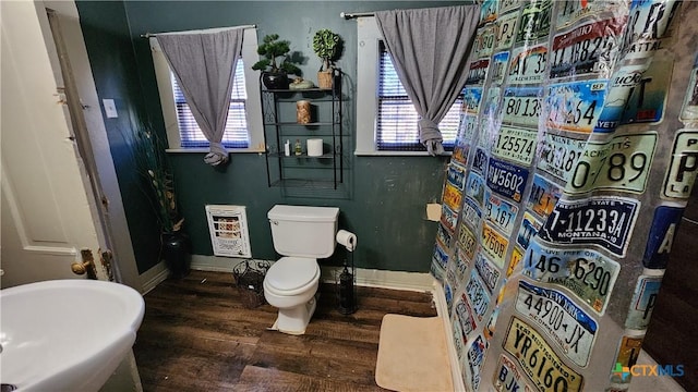 bathroom with toilet, wood-type flooring, a wealth of natural light, and heating unit