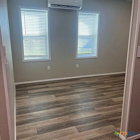 205 Lasalle Rd, Inez, TX 77968 - spare room with a wall mounted AC, plenty of natural light, dark wood finished floors, and baseboards