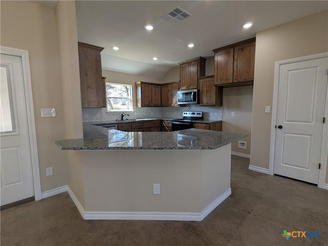 kitchen featuring vaulted ceiling, kitchen peninsula, decorative backsplash, dark stone counters, and appliances with stainless steel finishes