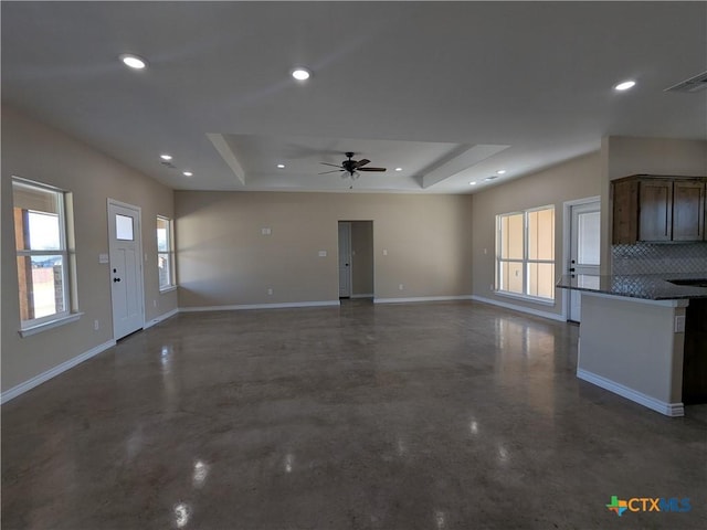 interior space with ceiling fan, a tray ceiling, and tasteful backsplash