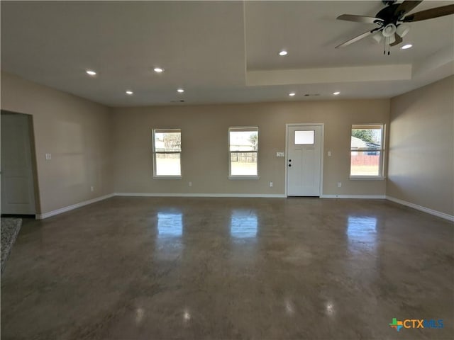 spare room featuring ceiling fan, a tray ceiling, and plenty of natural light