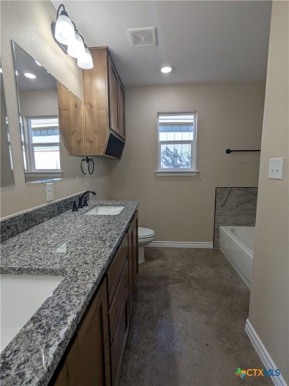 bathroom with toilet, a washtub, a healthy amount of sunlight, and vanity