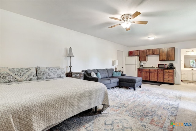 carpeted bedroom with ceiling fan, connected bathroom, white fridge, and sink