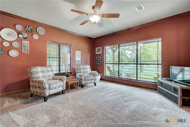 living area featuring a wealth of natural light, ceiling fan, and crown molding