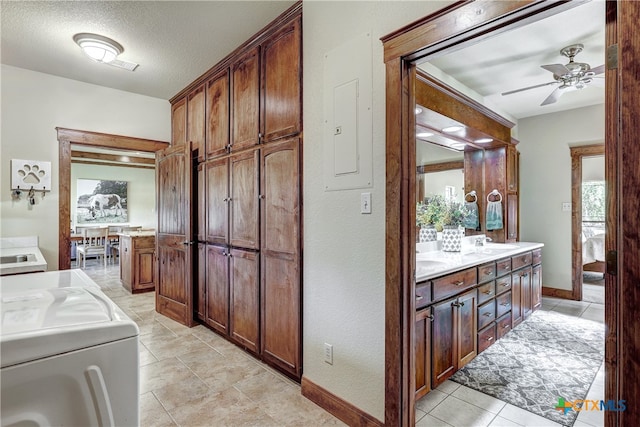 clothes washing area featuring cabinets, sink, ceiling fan, a textured ceiling, and washer / dryer