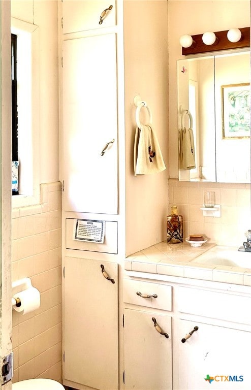 bathroom featuring vanity and tile walls