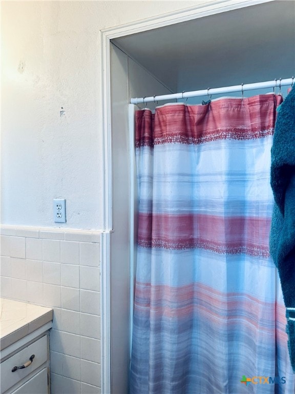 bathroom featuring vanity and tile walls