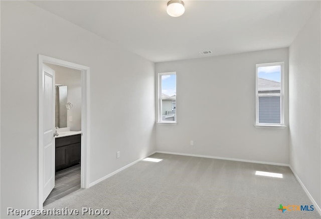 unfurnished bedroom featuring light carpet and connected bathroom