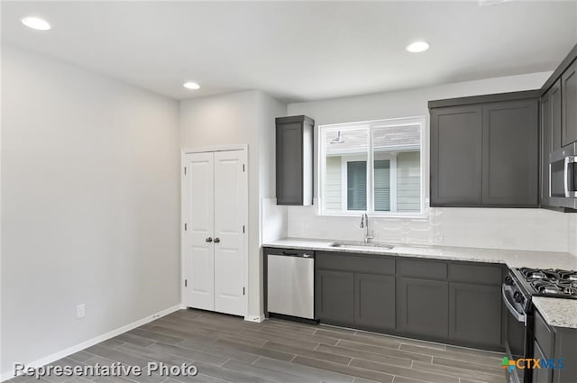 kitchen featuring backsplash, sink, light stone counters, appliances with stainless steel finishes, and dark hardwood / wood-style flooring