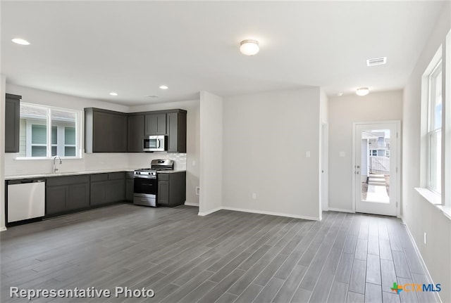 kitchen with appliances with stainless steel finishes, hardwood / wood-style flooring, plenty of natural light, and sink