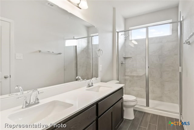 bathroom with a shower with door, vanity, hardwood / wood-style floors, and toilet