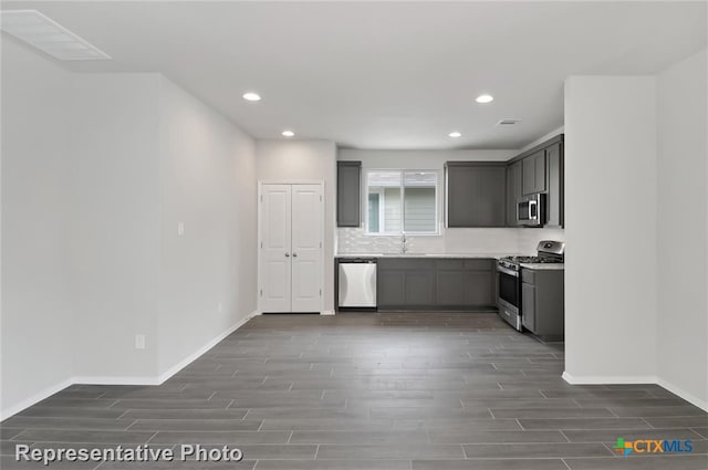 kitchen featuring appliances with stainless steel finishes, dark hardwood / wood-style floors, gray cabinetry, and sink