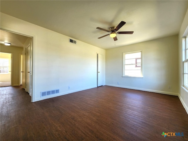 empty room with dark wood finished floors, baseboards, and visible vents