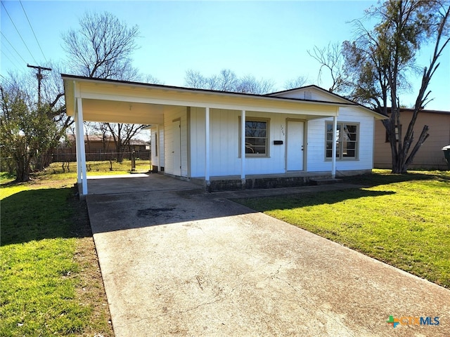 view of front facade featuring an attached carport, concrete driveway, a front lawn, and fence