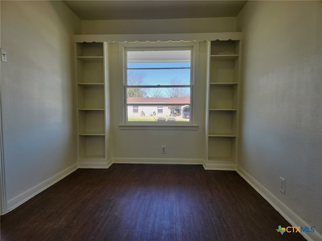 unfurnished room with dark wood finished floors and baseboards