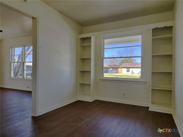 empty room featuring baseboards and dark wood-style flooring