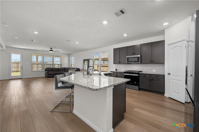 7703 Coral Key Dr, Northwest Harris, TX 77433 - kitchen featuring appliances with stainless steel finishes, light wood finished floors, light stone countertops, recessed lighting, and decorative backsplash