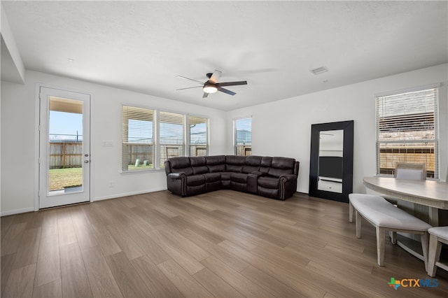 living room featuring a textured ceiling, light wood-type flooring, and ceiling fan