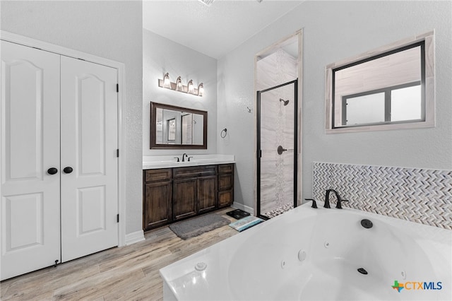 bathroom with wood-type flooring, vanity, and shower with separate bathtub