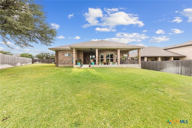 rear view of house with ceiling fan, a yard, and a patio