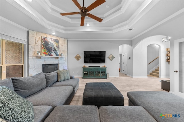 living room featuring a raised ceiling, wood-type flooring, and ornamental molding