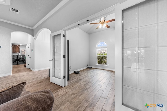 living room featuring light hardwood / wood-style flooring, ceiling fan, washing machine and dryer, ornamental molding, and a textured ceiling