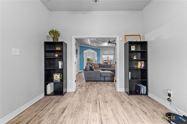 living area featuring ceiling fan, light hardwood / wood-style floors, ornamental molding, and a tray ceiling