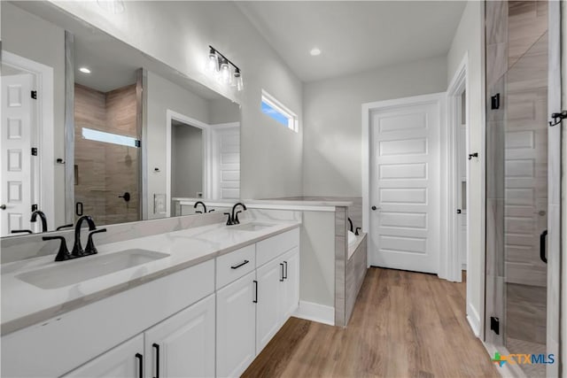 113 Cobblestone Ln, Burnet, TX 78611 - full bathroom with wood finished floors, a sink, double vanity, and a stall shower