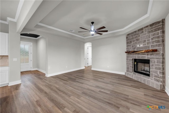 113 Cobblestone Ln, Burnet, TX 78611 - unfurnished living room with wood finished floors, a tray ceiling, visible vents, and a fireplace