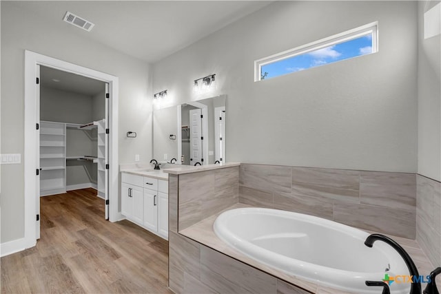 113 Cobblestone Ln, Burnet, TX 78611 - full bathroom with a bath, visible vents, wood finished floors, vanity, and a walk in closet