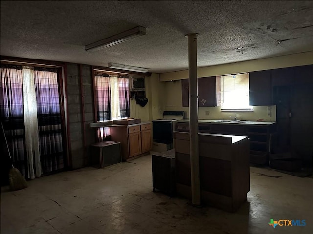 kitchen with a sink, a textured ceiling, and electric range oven