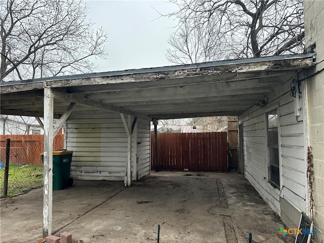 view of vehicle parking featuring an attached carport and fence