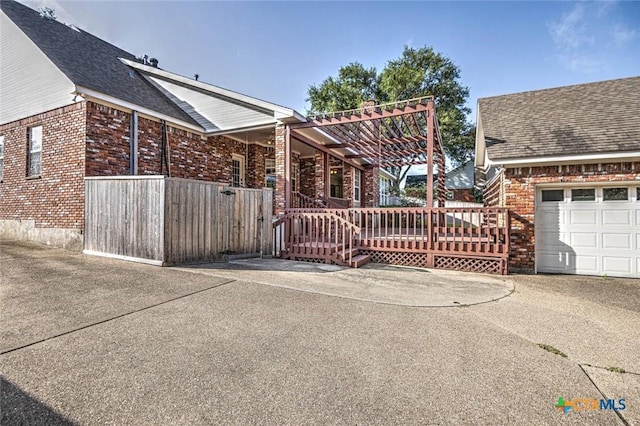 view of gate with a garage and a wooden deck