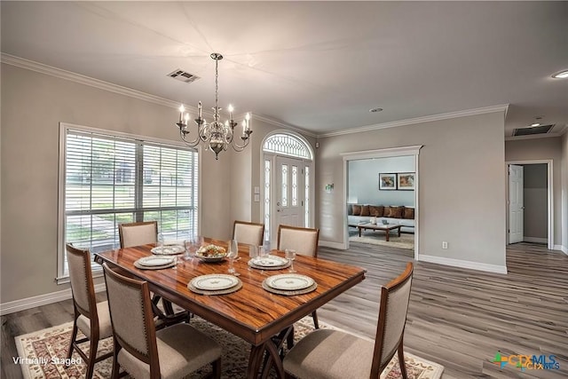 dining room with crown molding, an inviting chandelier, and hardwood / wood-style flooring