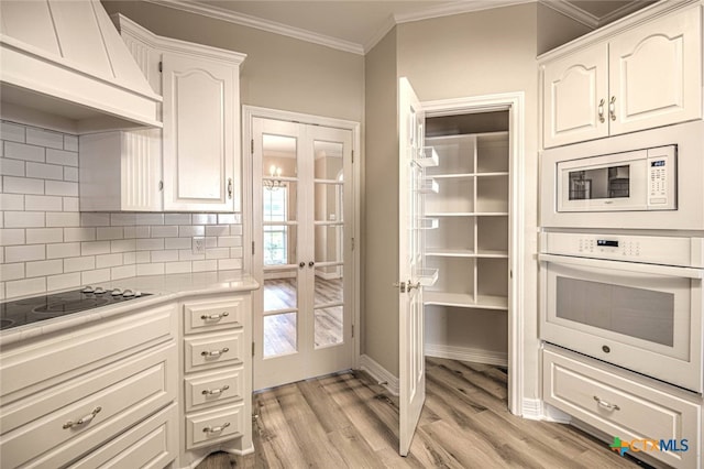 kitchen with premium range hood, french doors, white cabinets, and white appliances