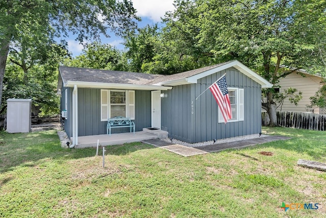 view of front of home featuring a front lawn, covered porch, and a storage shed