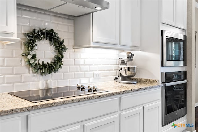 kitchen featuring white cabinets, backsplash, stainless steel appliances, and light stone countertops