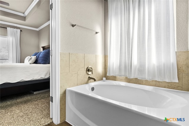 bathroom featuring a washtub, crown molding, and tile walls