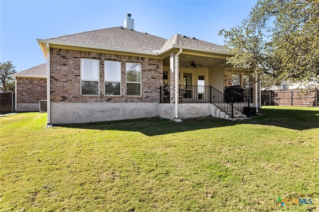 rear view of house featuring a lawn and ceiling fan